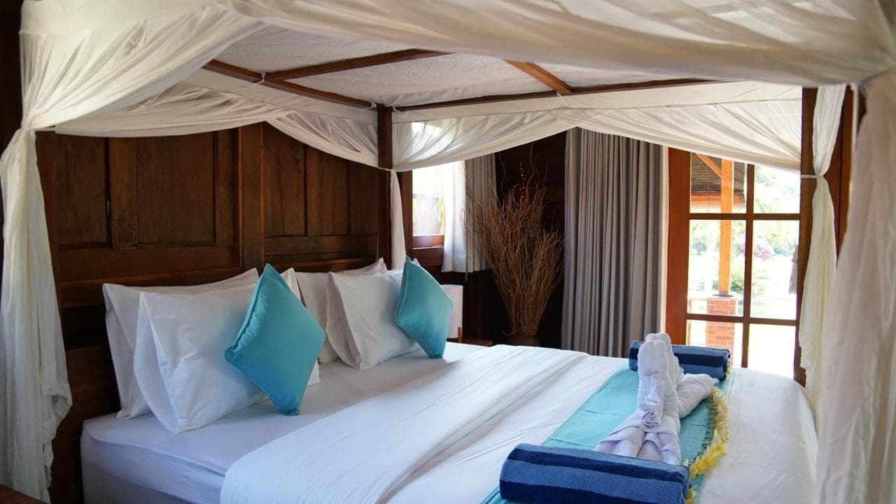 a bedroom with a large bed with a canopy at Kubu Kangin Resort in Amed