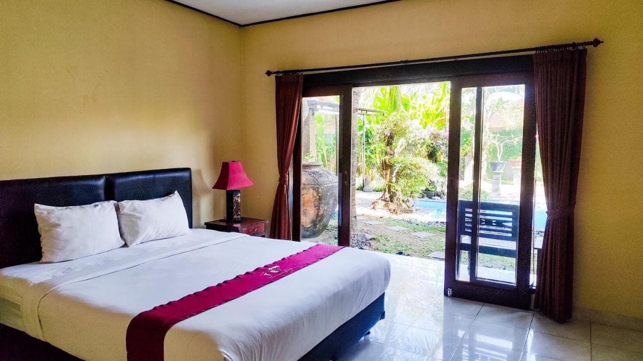 a bedroom with a bed and a sliding glass door at Oemah Bali in Nusa Dua
