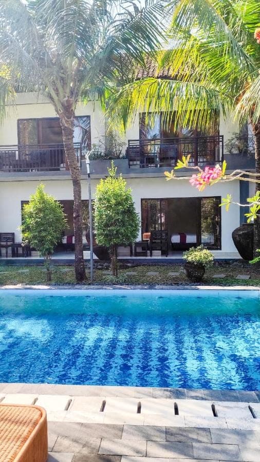 a resort with a swimming pool in front of a building at Oemah Bali in Nusa Dua