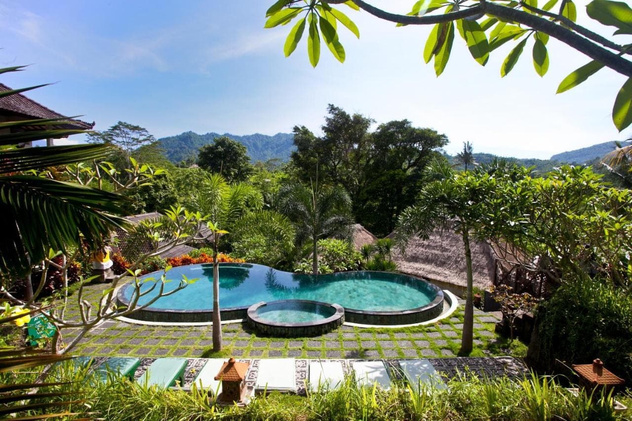 a swimming pool in the middle of a garden at Uma Agung Villa in Sidemen