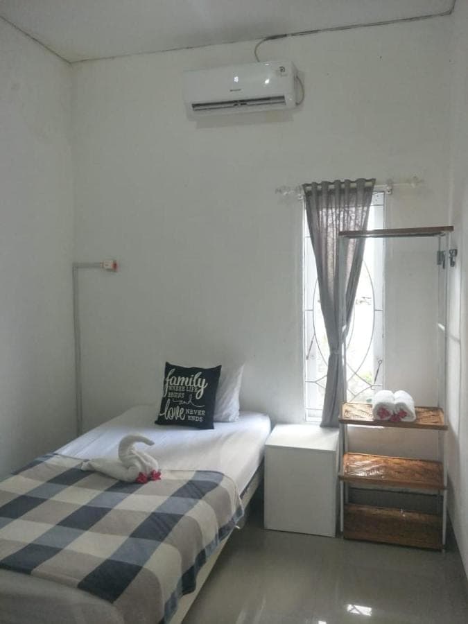 a small bedroom with a bed and a window at Pigeon House Nusa Dua in Nusa Dua