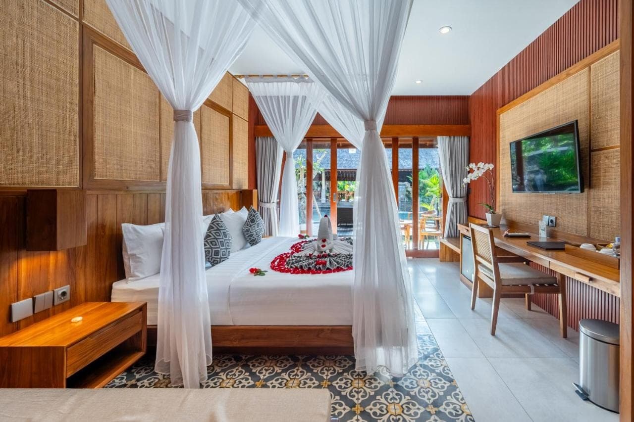 a bedroom with a bed with curtains and a desk at Puri Andong Villa in Ubud