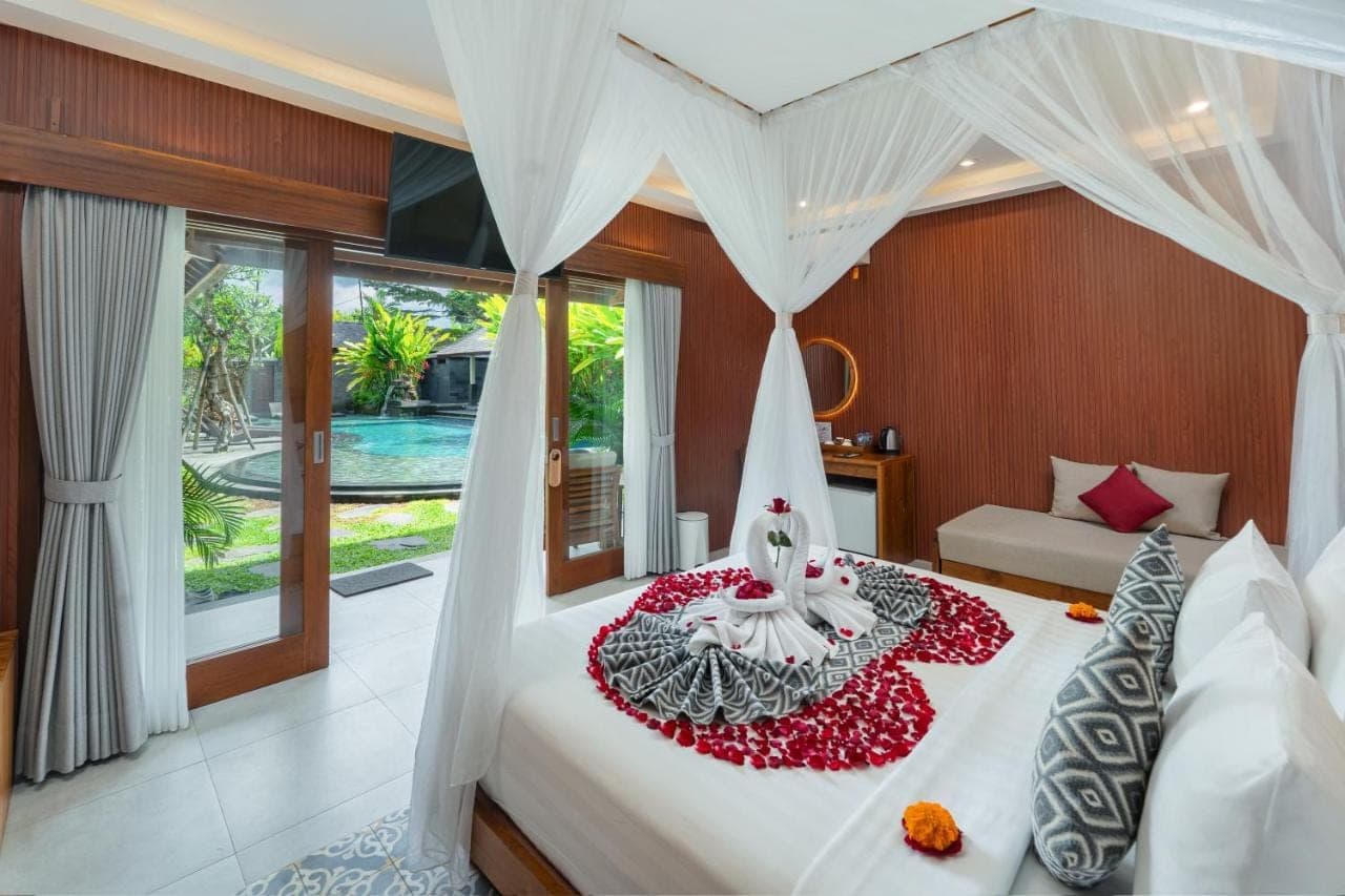 a bedroom with a bed with a white canopy at Puri Andong Villa in Ubud