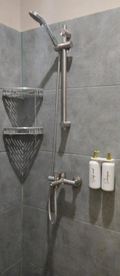 a shower with a faucet and two cups in a bathroom at Langoon House in Uluwatu
