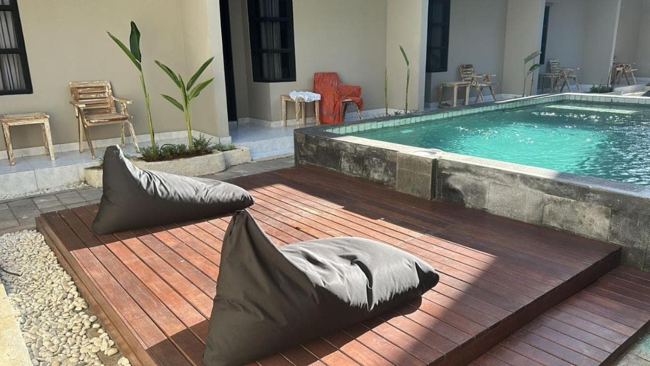 a swimming pool with pillows sitting on a wooden deck at Langoon House in Uluwatu