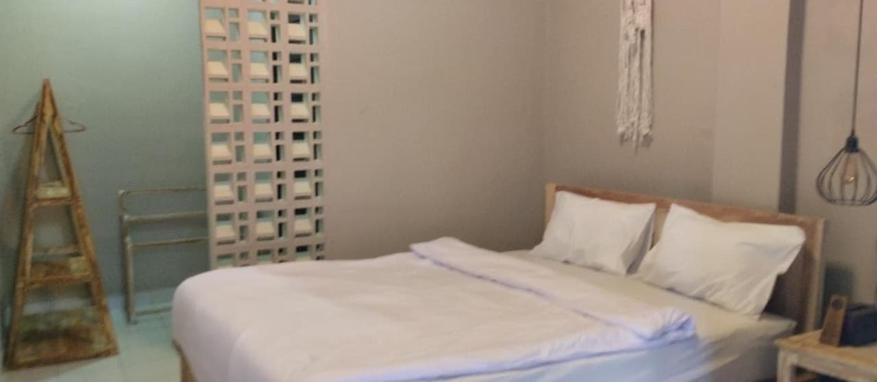 a bed with white sheets and pillows in a room at Langoon House in Uluwatu
