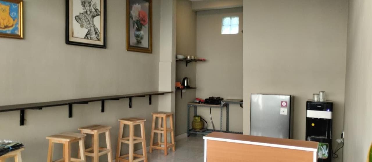 a room with a kitchen with stools and a refrigerator at Langoon House in Uluwatu