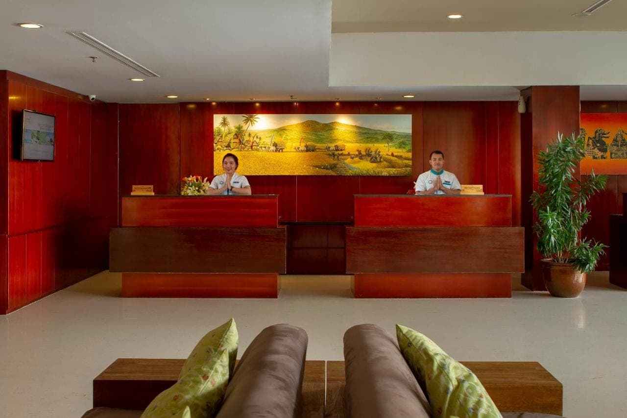 two people sitting at the reception desks in a hotel lobby at PrimeBiz Hotel Kuta in Kuta