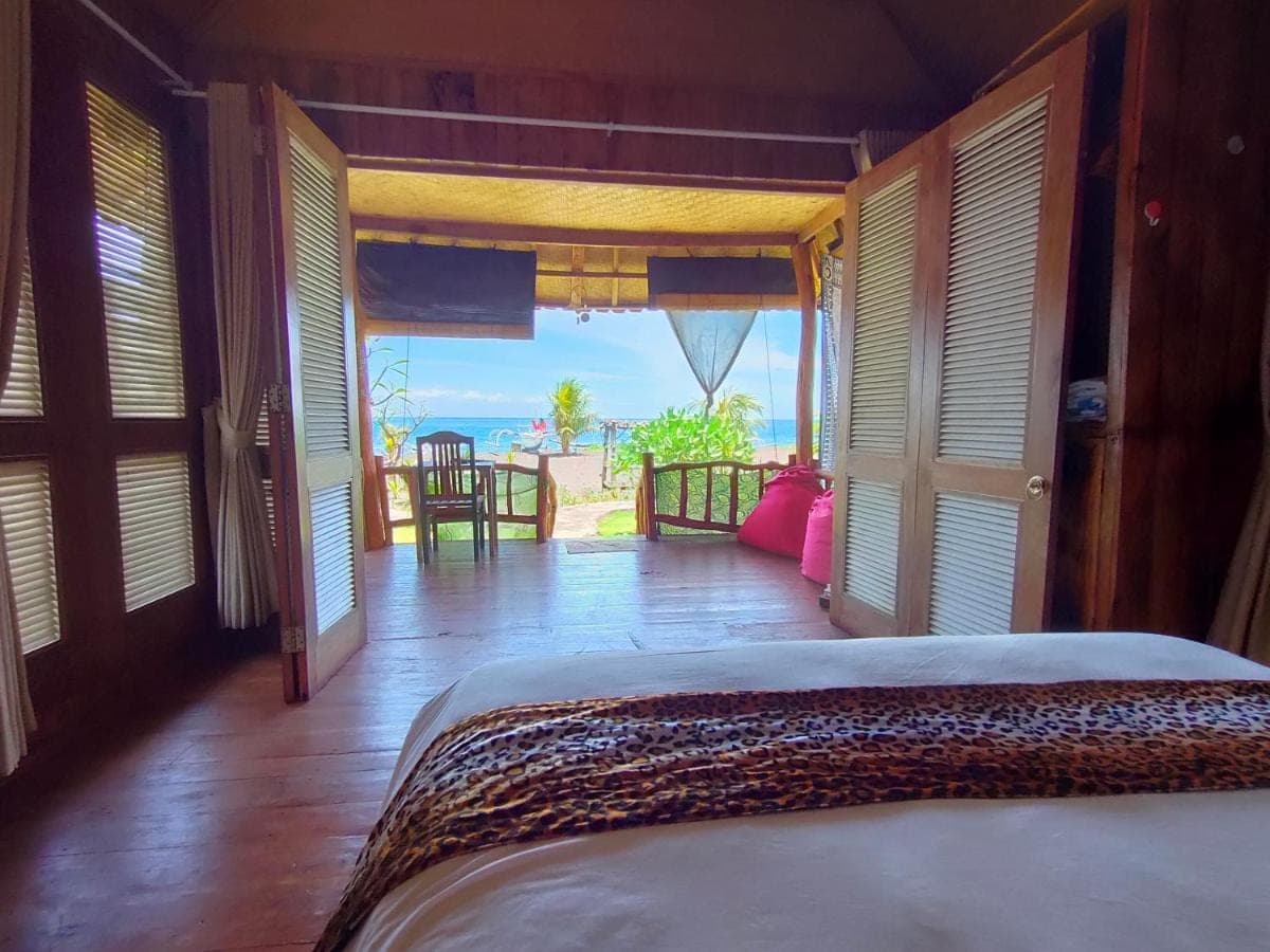 a bedroom with a bed and a view of the ocean at Yogi Beach Cabin in Amed