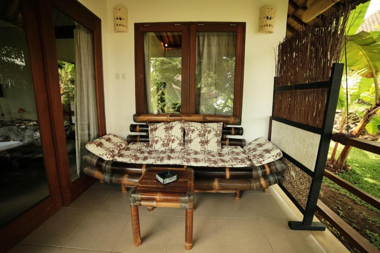 a living room with a bench and a window at Bali Dream House in Amed