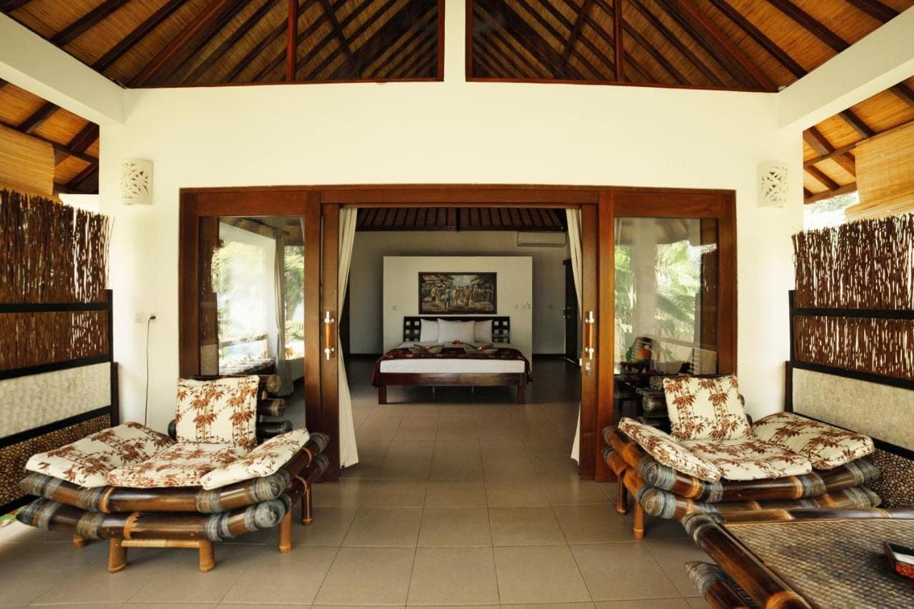 a room with a bedroom with a bed and chairs at Bali Dream House in Amed