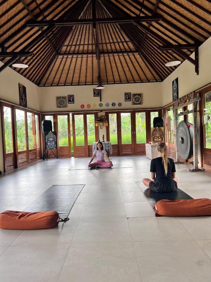 two women sitting on the floor in a yoga class at Subak Tabola Villa in Sidemen