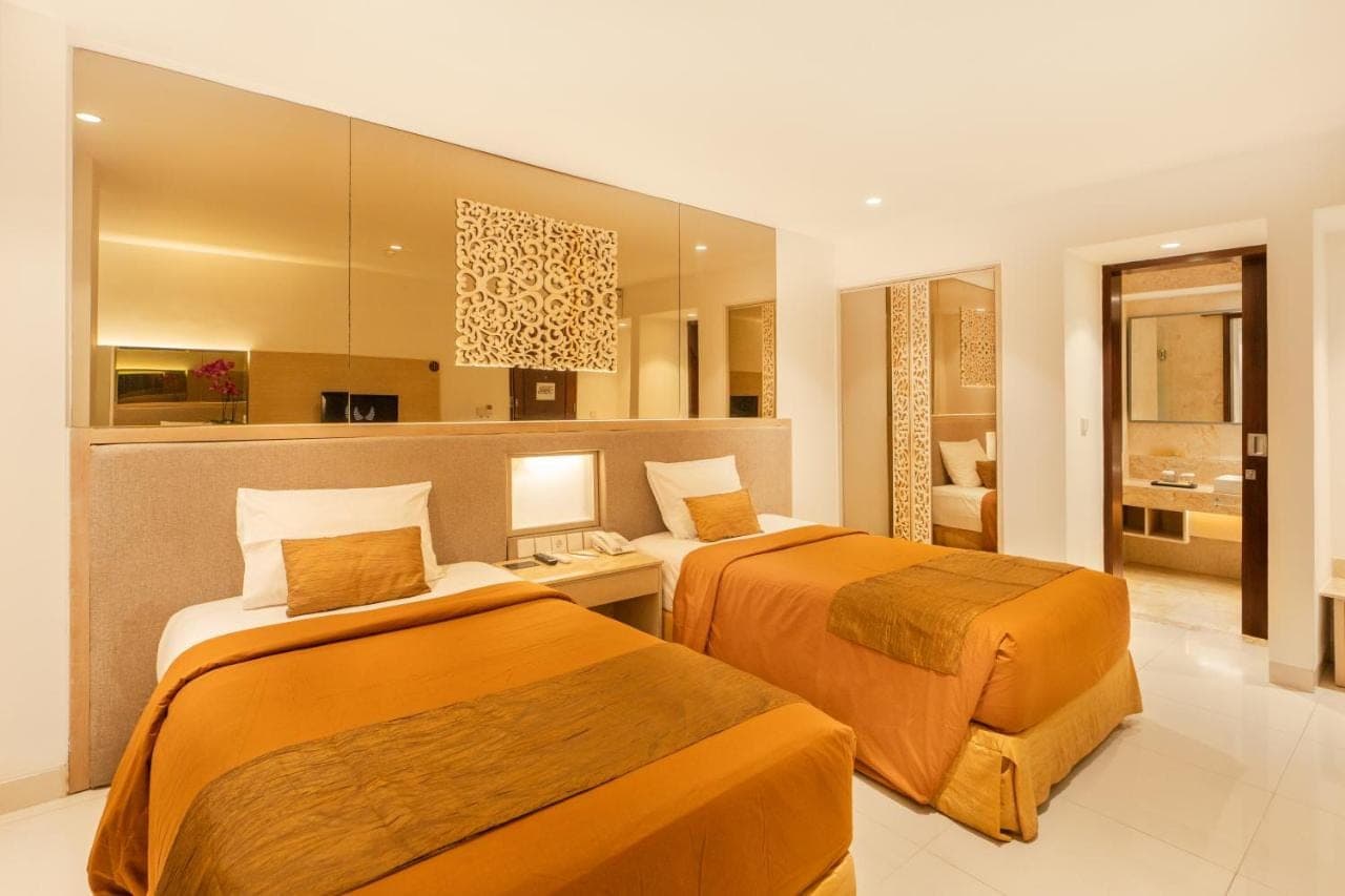 a hotel room with two beds and a bathroom at Kuta Angel Hotel in Kuta