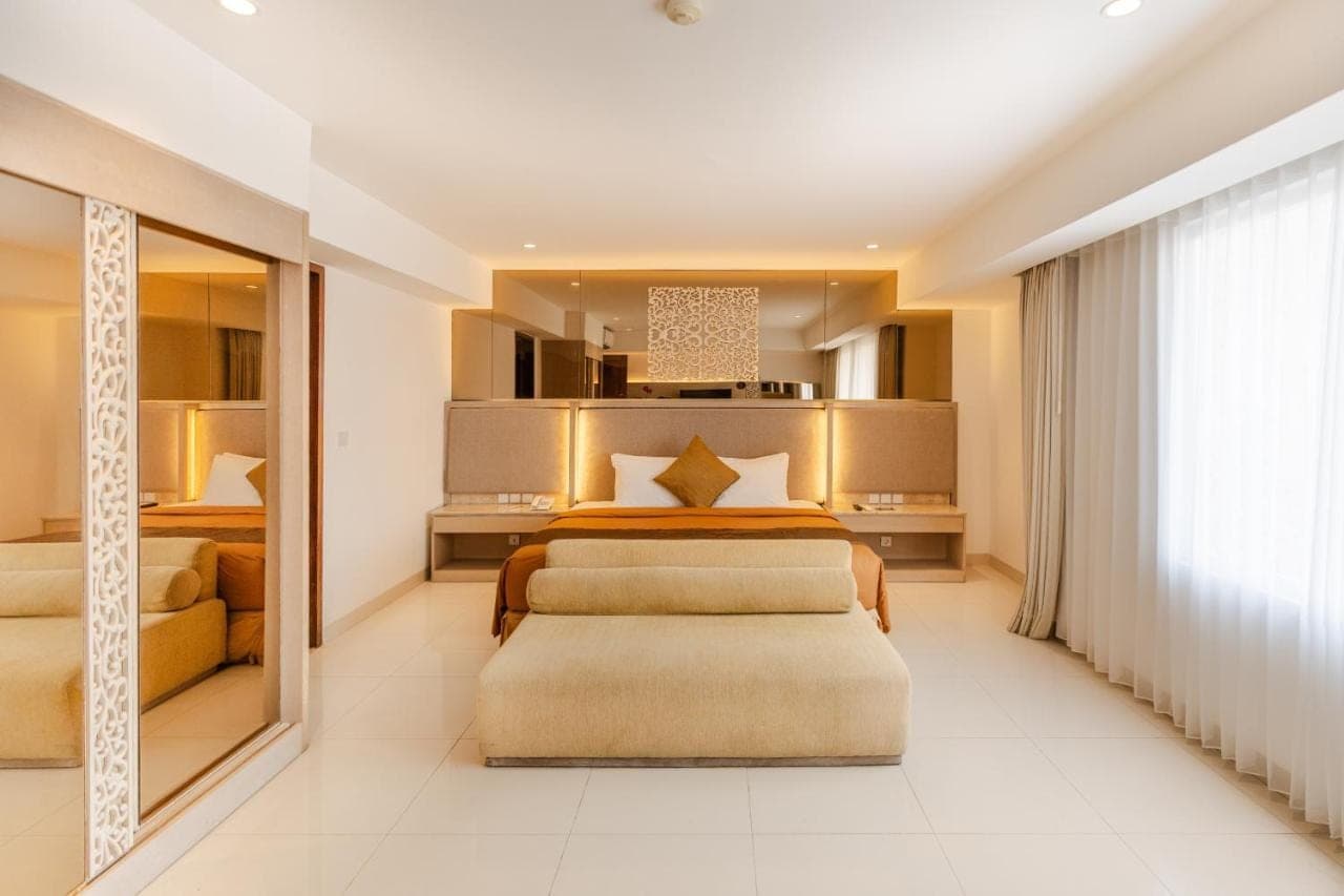a bedroom with two beds and a large window at Kuta Angel Hotel in Kuta