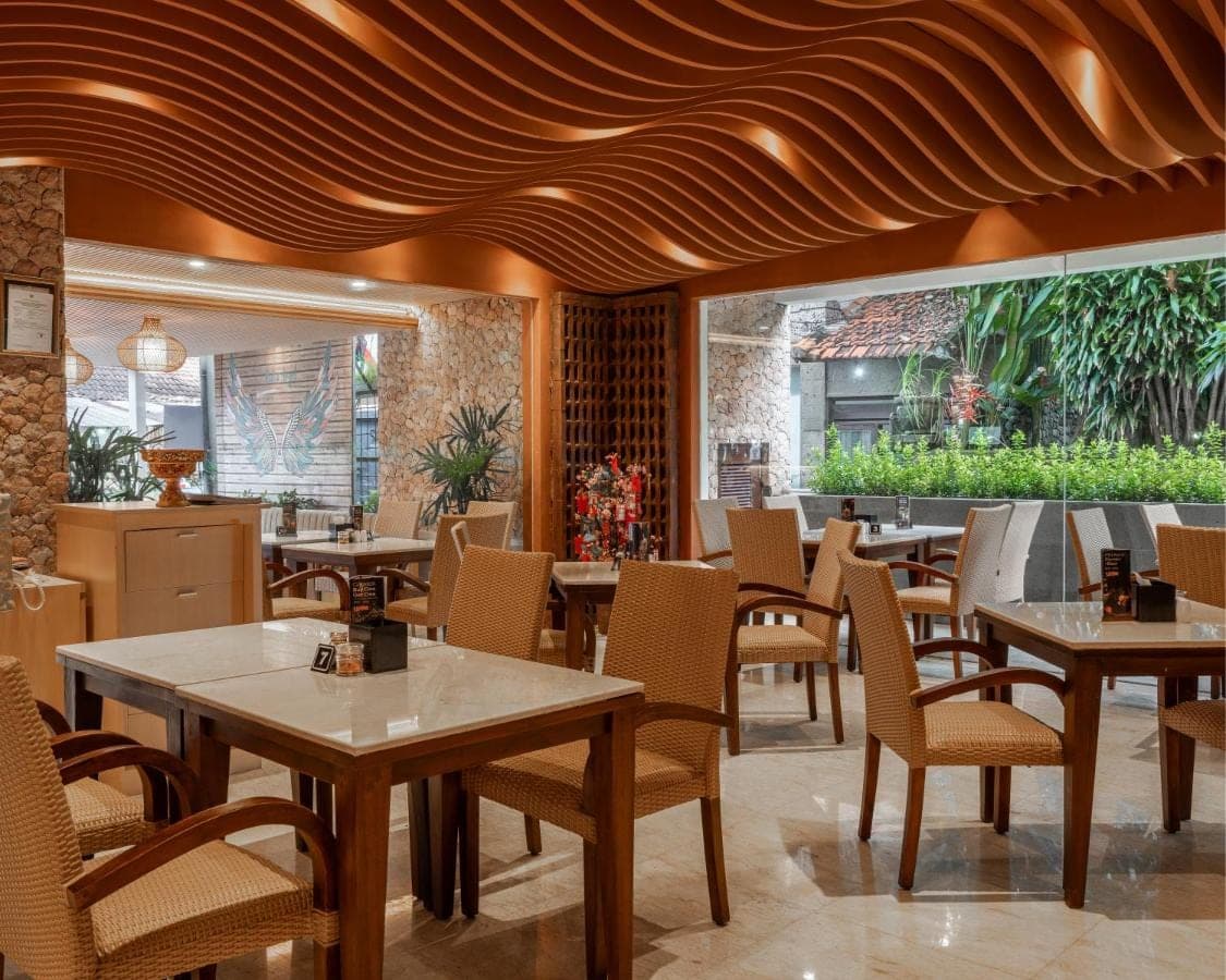 a restaurant with tables and chairs in a room at Kuta Angel Hotel in Kuta