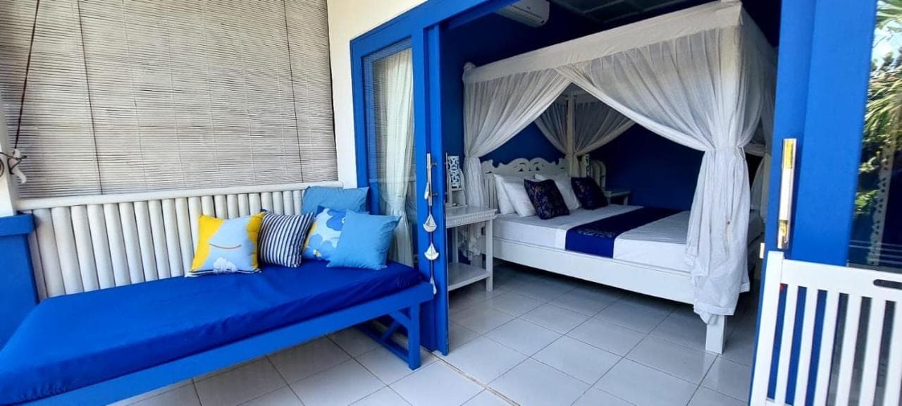 a blue and white bedroom with a canopy bed at The Shooting Star Homestay in Amed