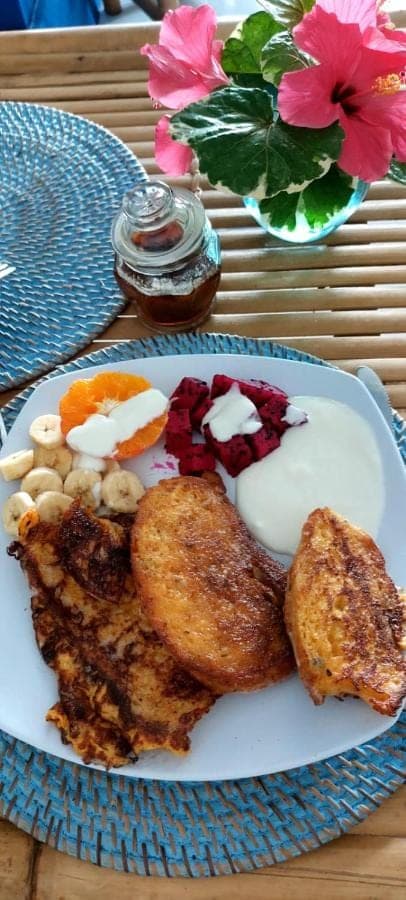 a plate of food with eggs and meat on a table at The Shooting Star Homestay in Amed