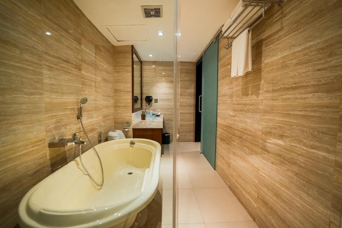 a bathroom with a tub and a sink at The Nest Hotel Nusa Dua in Nusa Dua