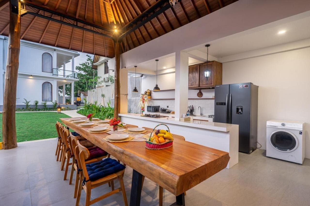 a kitchen and dining room with a wooden table and chairs at The Cokelat Amed in Amed