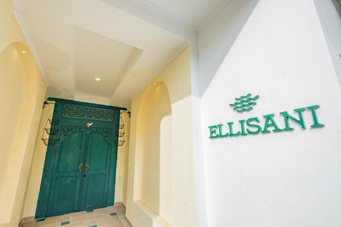 a green door in a building with a sign on the wall at Ellisani Bali in Canggu