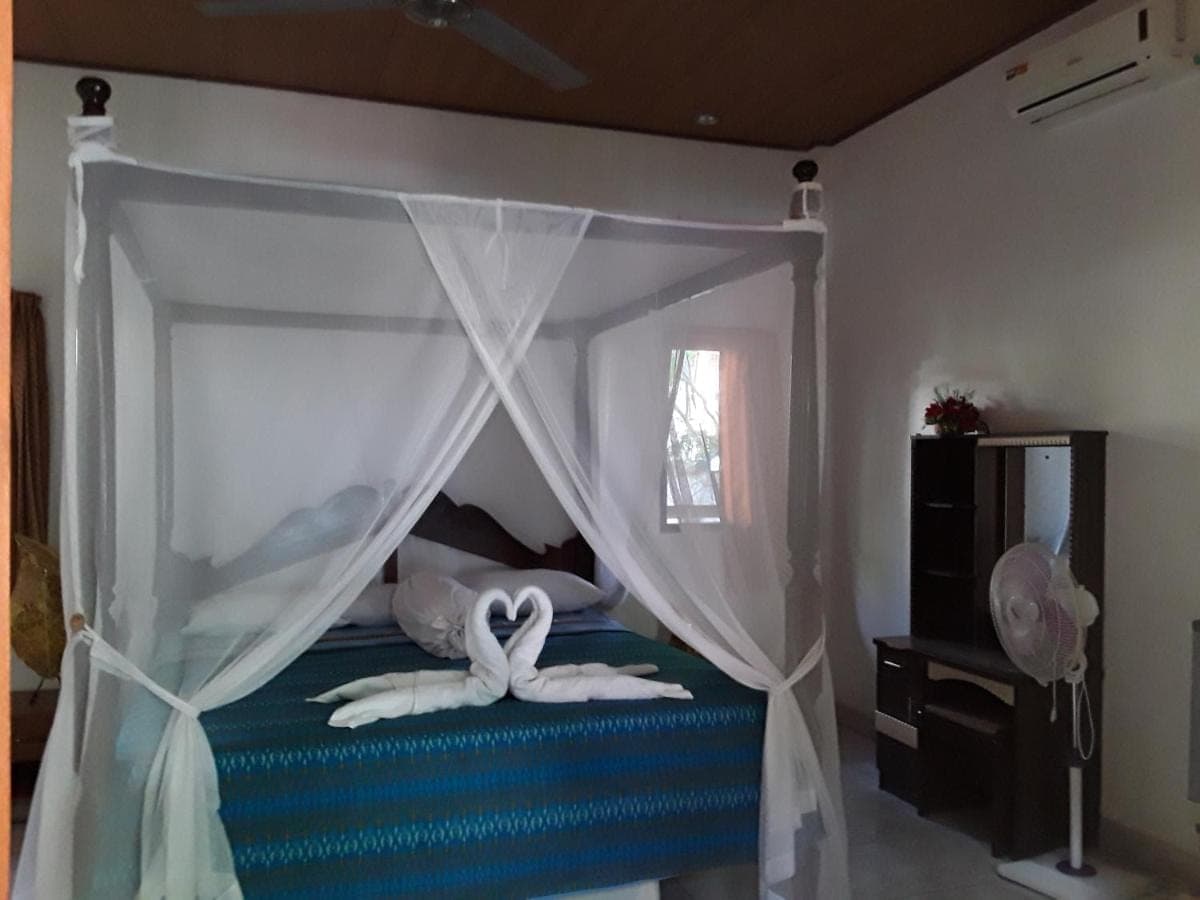 a bedroom with a canopy bed with swans on it at Blue Star Bungalows &amp; Cafe in Amed