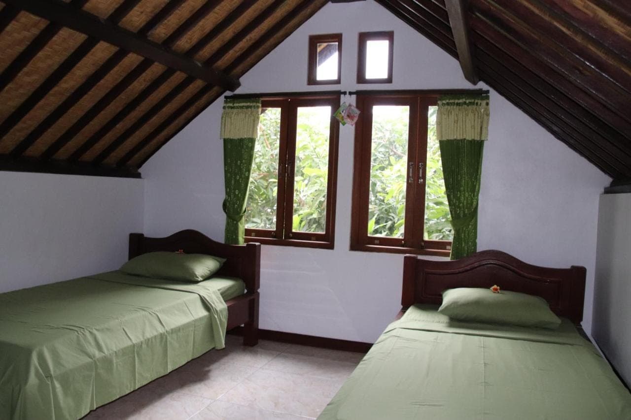 two beds in a room with windows at Blue Star Bungalows &amp; Cafe in Amed
