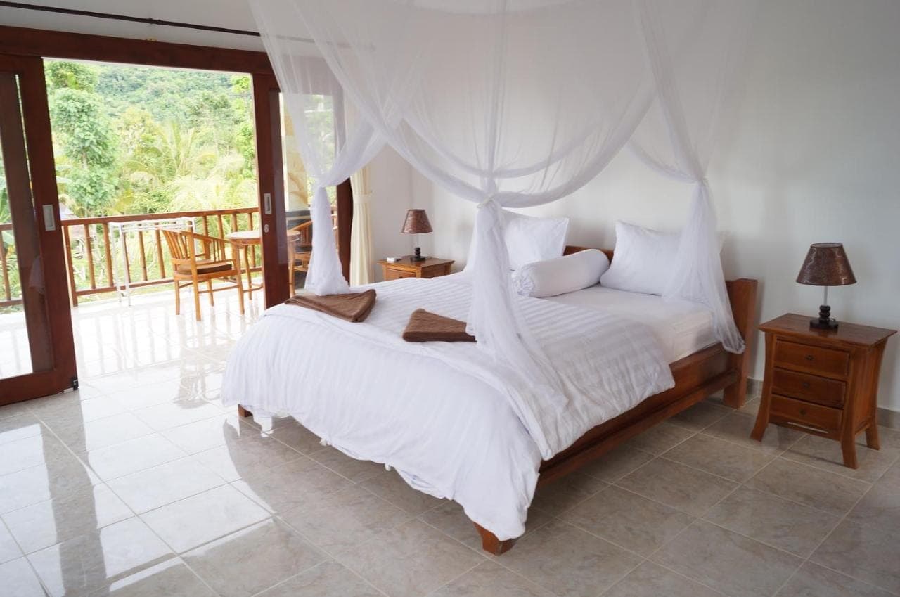 a bedroom with a white bed with a canopy at Villa Mangga Beach in Amed