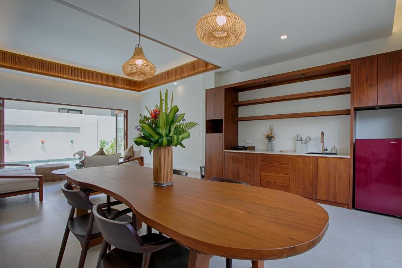 a dining room and living room with a wooden table at My Villa and Resort Canggu in Canggu