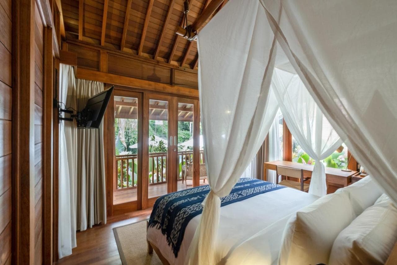 a bedroom with a bed with a white canopy at Samujha Ubud Resort in Ubud