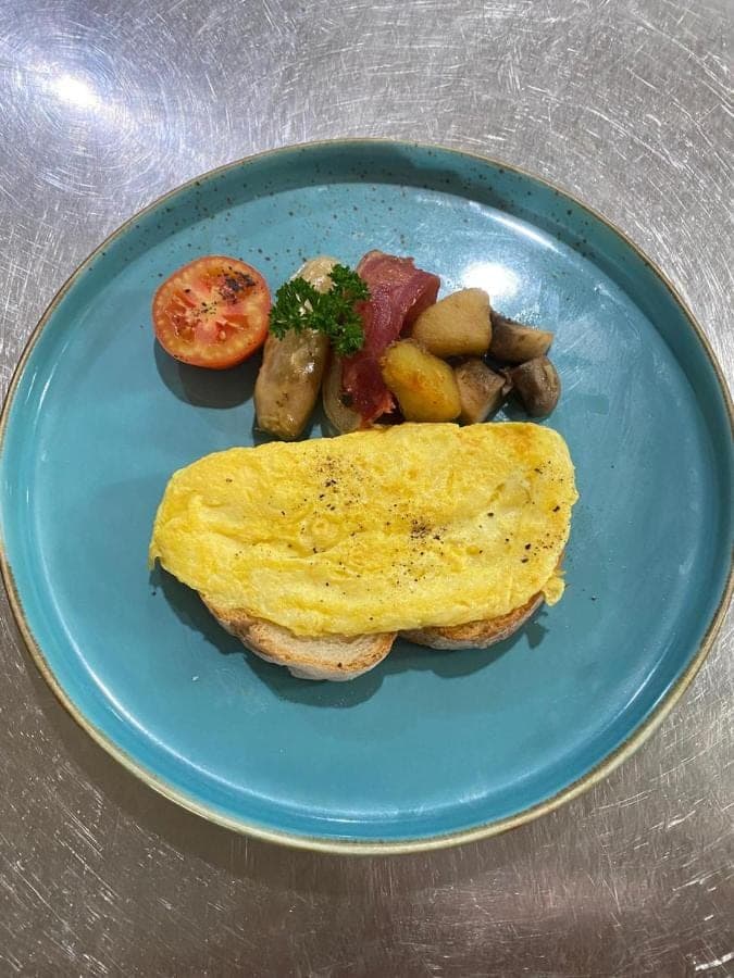 a blue plate of food with an omelet and potatoes at Samujha Ubud Resort in Ubud