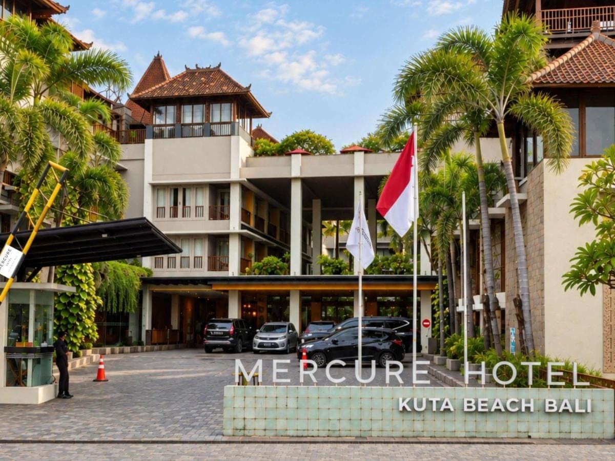 a hotel with palm trees in front of it at Mercure Kuta Bali in Kuta