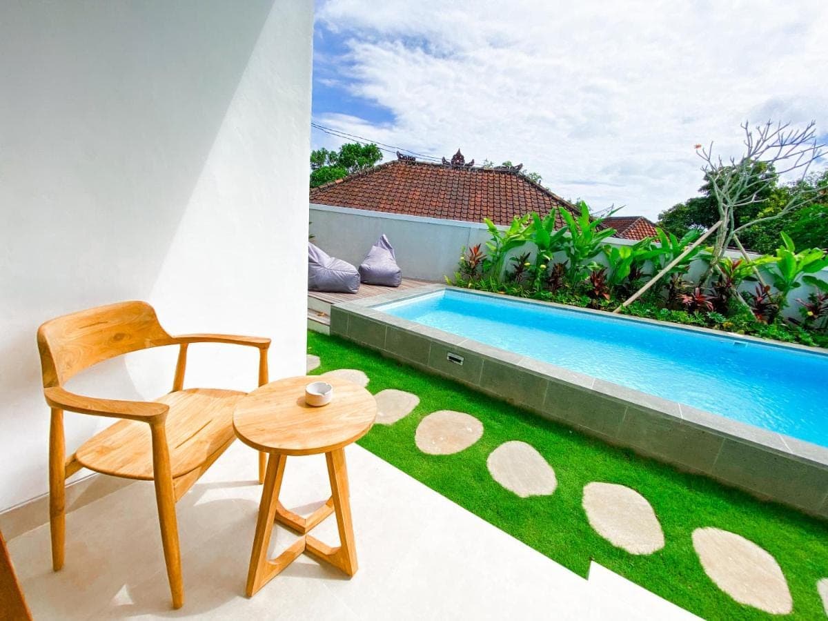 a chair and a table next to a swimming pool at Casa de Ambalia in Uluwatu