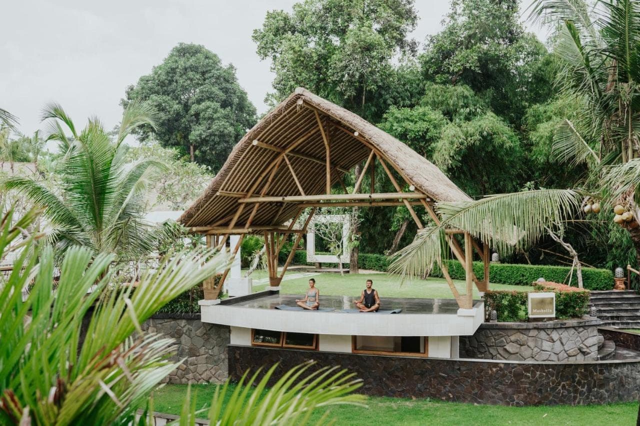 two men sitting on a pool in a garden at Harsono Boutique Resort Bali in Sanur