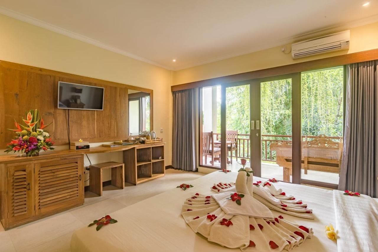 a bedroom with a large bed with a large window at Alamdini Resort Ubud in Ubud
