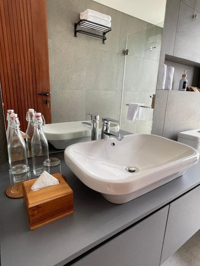 a bathroom with a white sink and a mirror at Widji Garden Villa in Uluwatu