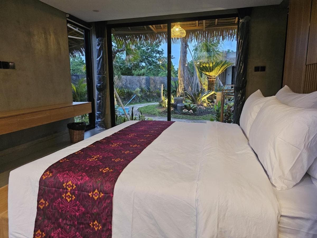 a bedroom with a large white bed and a window at Widji Garden Villa in Uluwatu