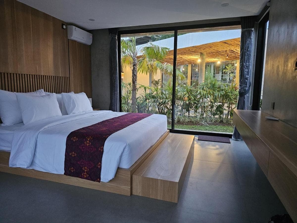 a bedroom with a large bed and a large window at Widji Garden Villa in Uluwatu