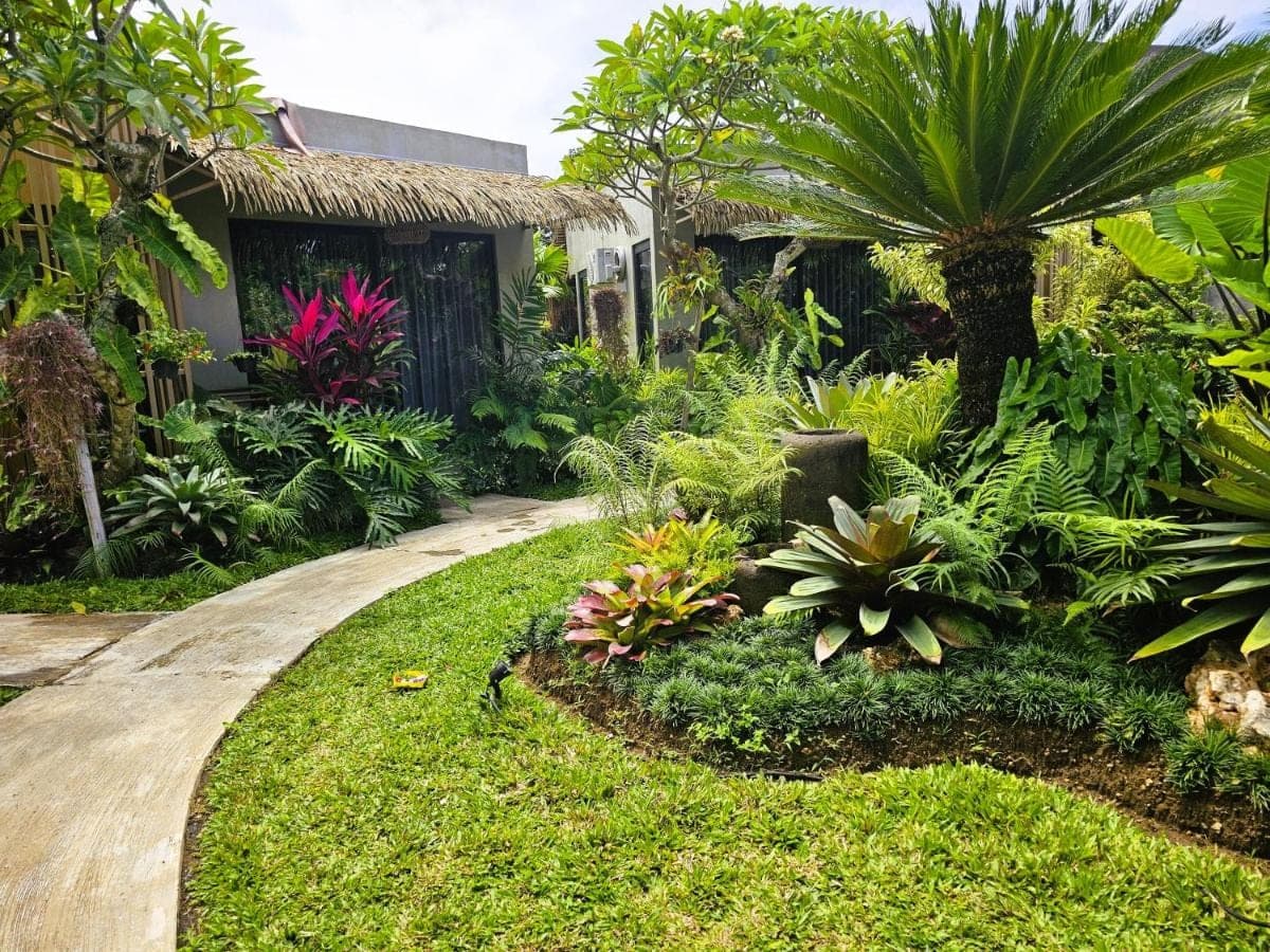 a garden with a walkway in front of a house at Widji Garden Villa in Uluwatu
