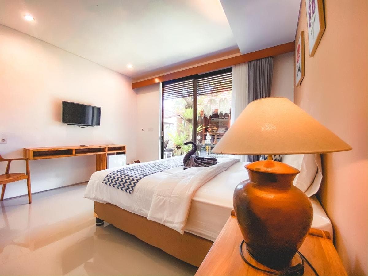 a bedroom with a bed and a lamp on a table at Radha Homestay in Sanur