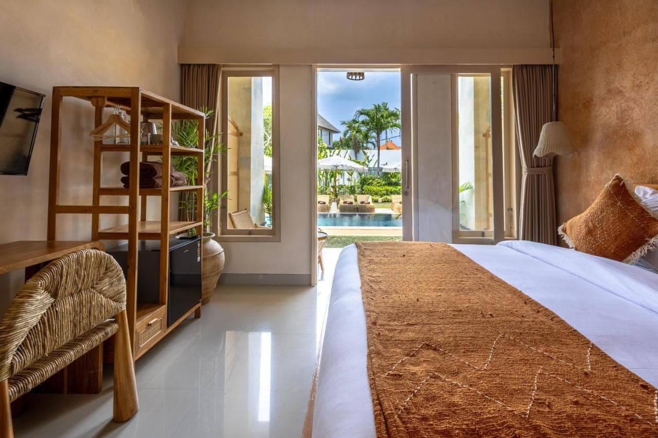 a bedroom with a bed and a view of a pool at KALM Bali in Canggu