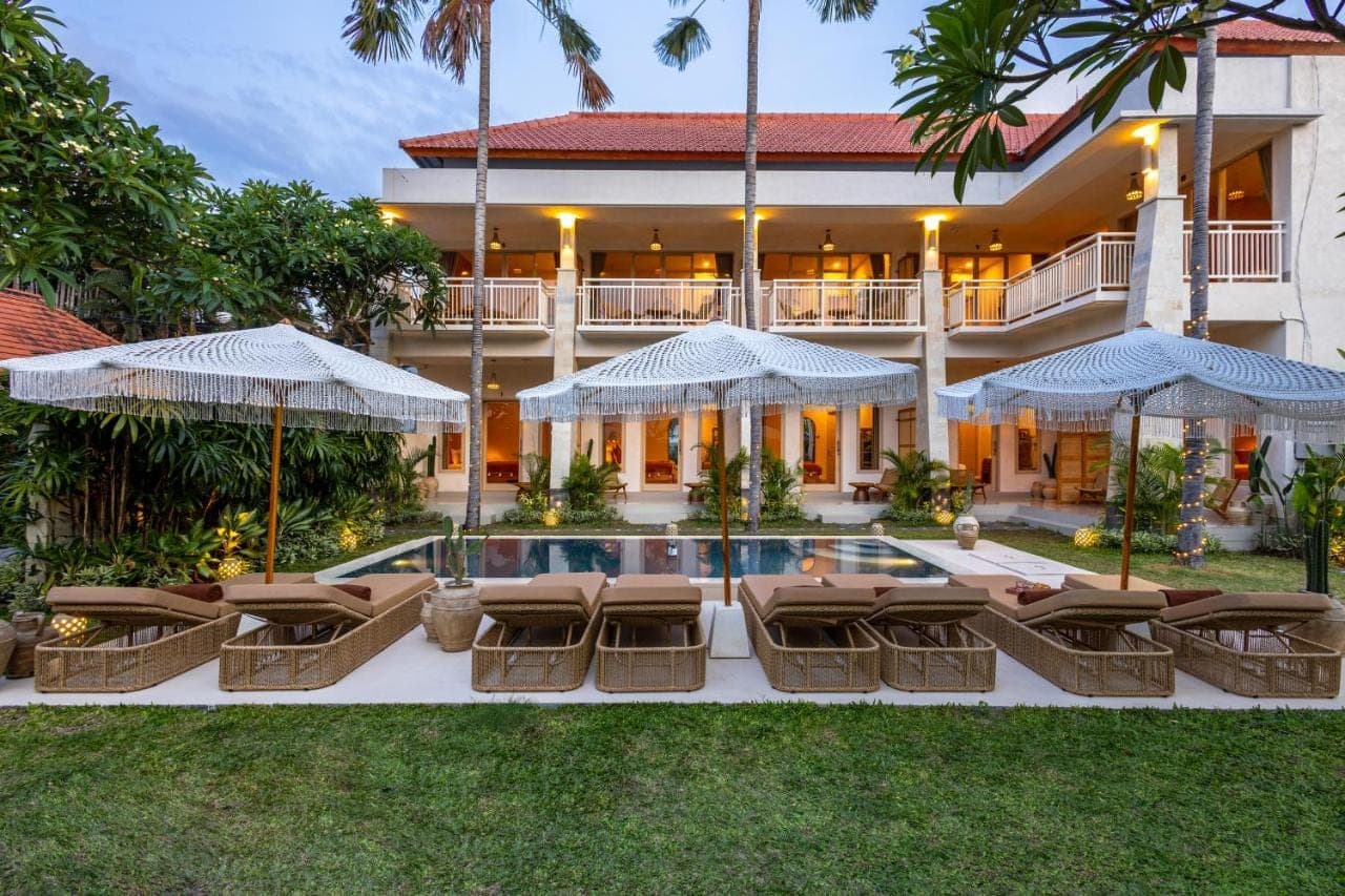 an exterior view of a resort with lounge chairs and a swimming pool at KALM Bali in Canggu