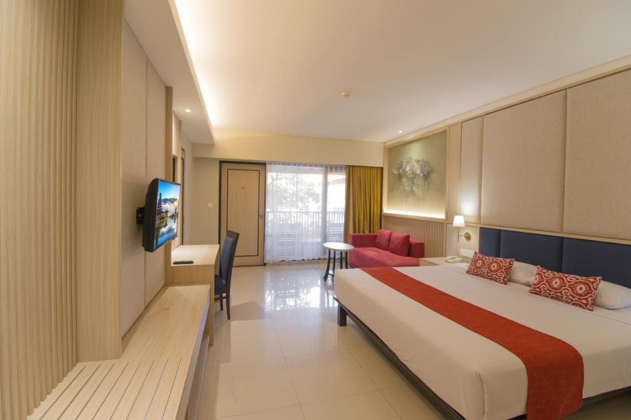 a hotel room with a bed and a tv at Bali Rani Hotel in Kuta
