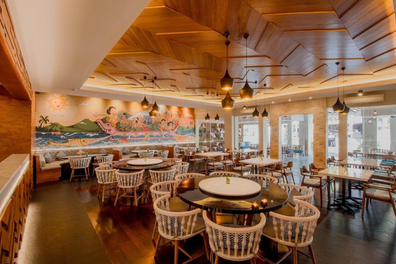a restaurant with tables and chairs and a large mural at Bali Rani Hotel in Kuta