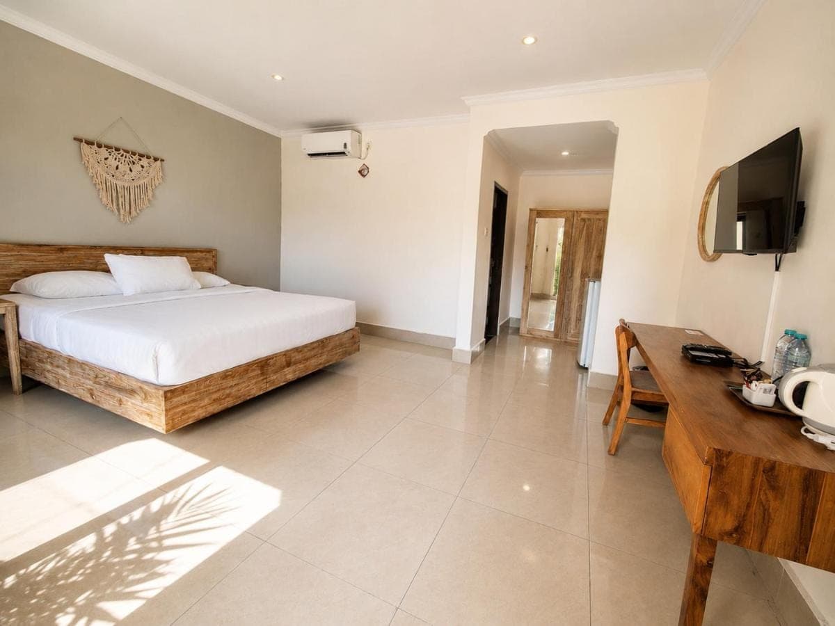 a bedroom with a bed and a desk and a television at Radha Bali Hotel in Kuta