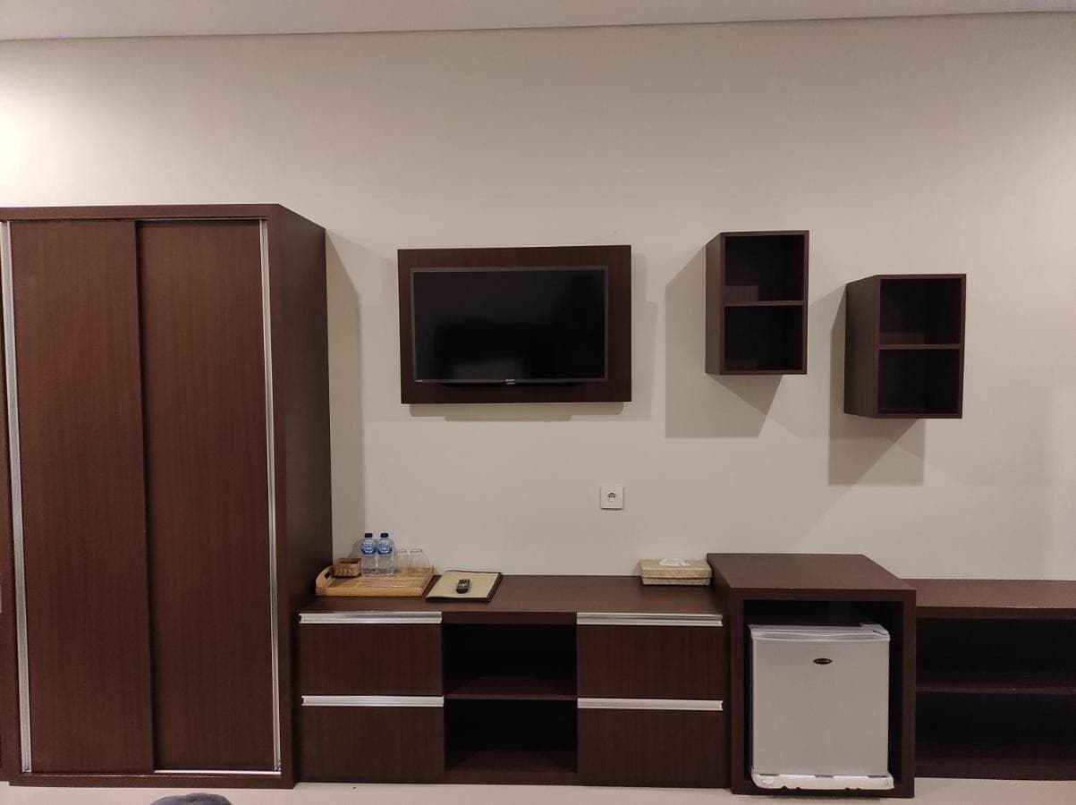 a room with a desk and a tv on the wall at Kubu Di-Kayla's in Sanur