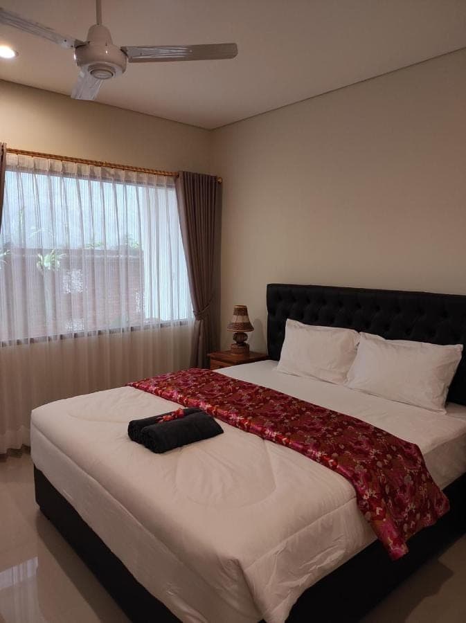 a bedroom with two beds with a red blanket on it at Kubu Di-Kayla's in Sanur