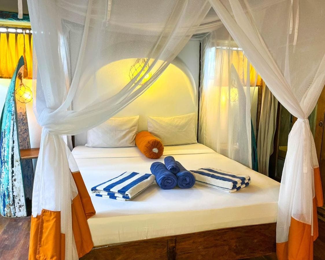 a white canopy bed with blue towels on it at Blue Earth Village in Amed