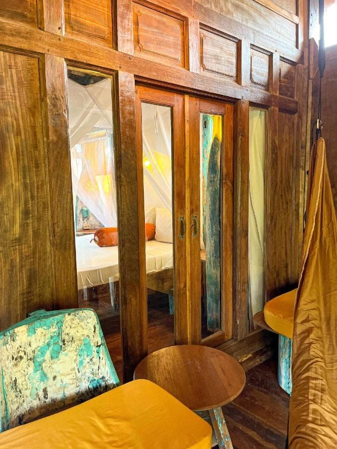 a room with wooden walls and a bed and a chair at Blue Earth Village in Amed