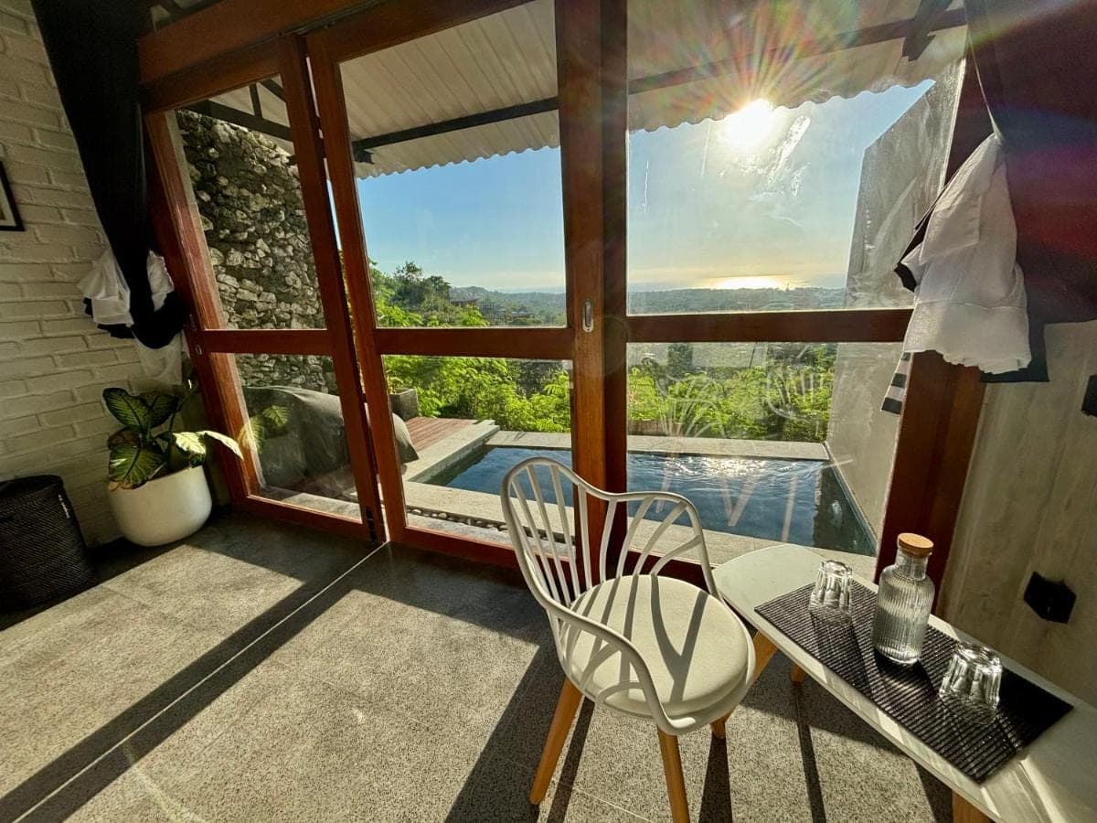 a room with a table and a chair and a pool at Padawatu Villas in Uluwatu