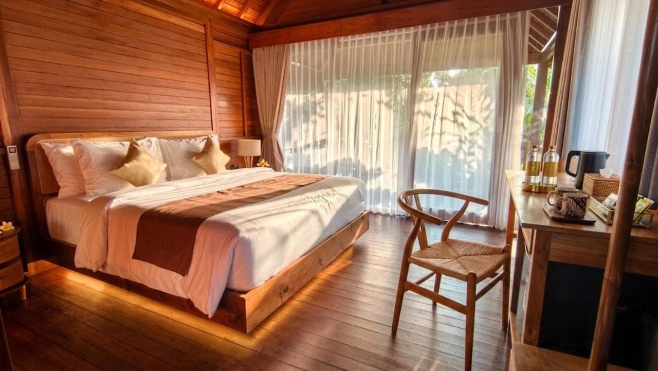 a bedroom with a bed and a desk and a chair at The Woods Uluwatu in Uluwatu